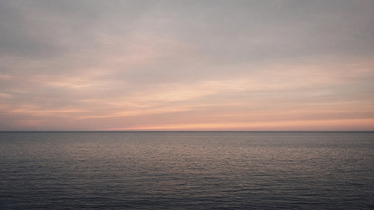 Open sea at dusk with the horizon running through the exact center of the frame, splitting water and sky into even bands